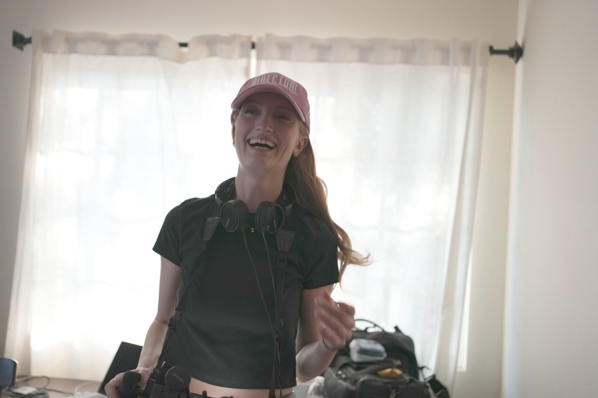 Chelsey Kaye on set wearing a DIRECTOR cap and headphones, smiling