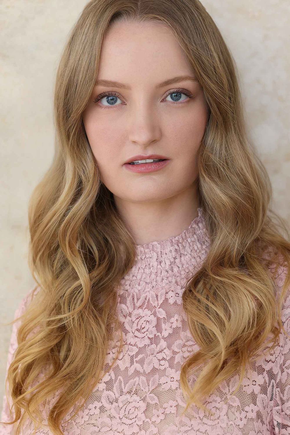 Headshot of Chelsey Kaye, smiling softly in a pink lace top